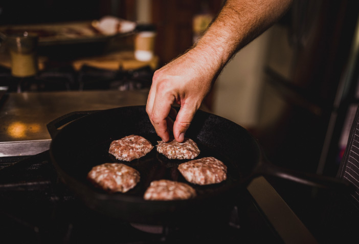 Cured sausage patties being fried in cast iron skillet