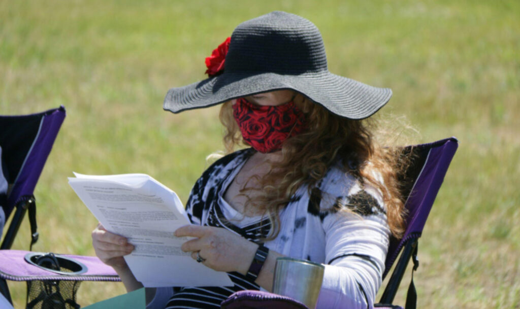 a woman wearing a face mask while reading outside